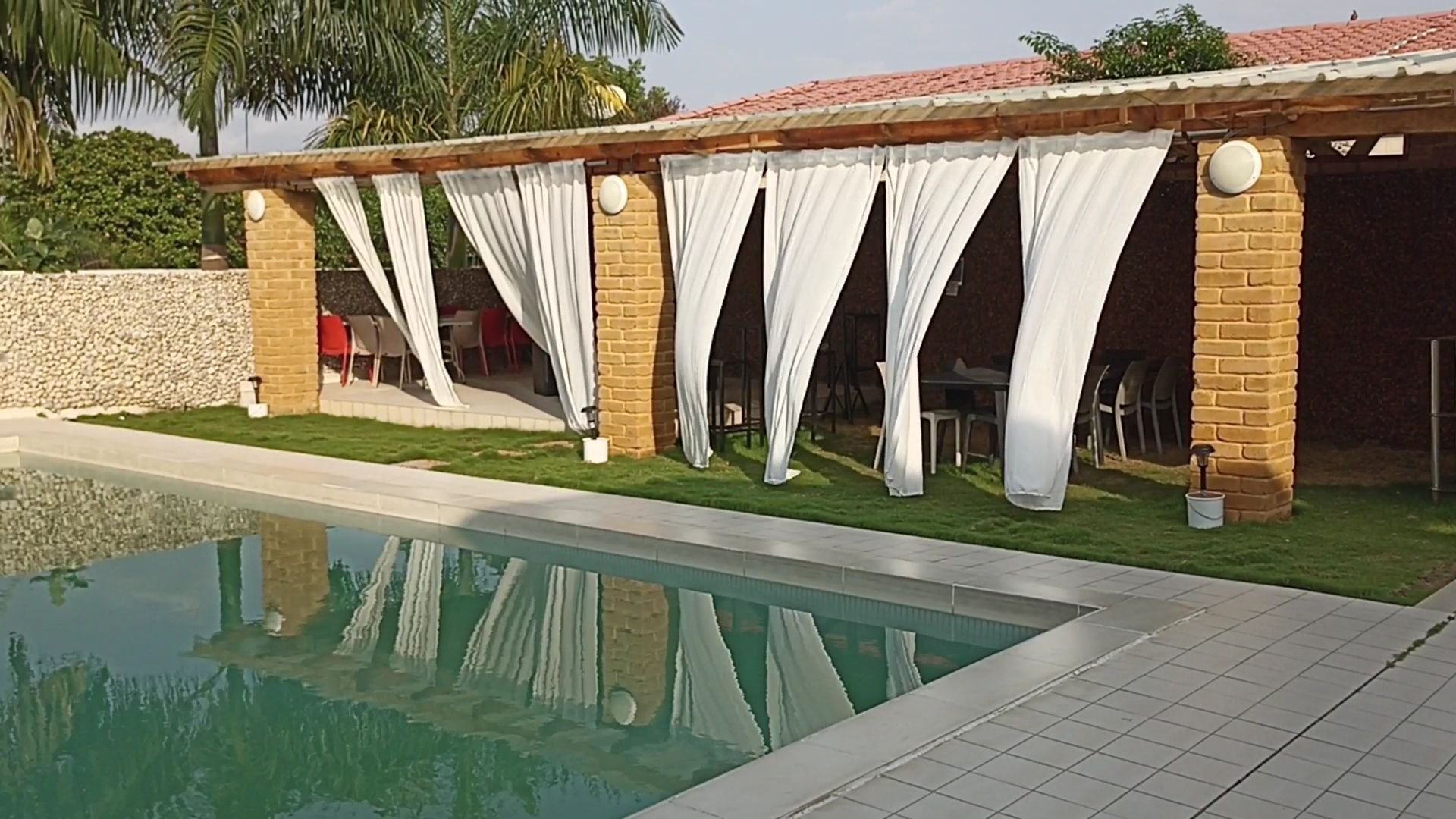 La piscine et le pavillon aux voilages blancs